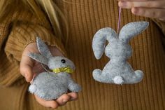 a person holding two stuffed animals in their hands, one is gray and the other is white