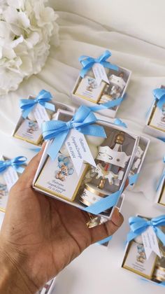 a person holding a small box with some baby items in it's hand and blue ribbon around the top