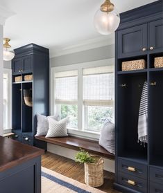 a room that has some blue cabinets in it and a window seat with pillows on it