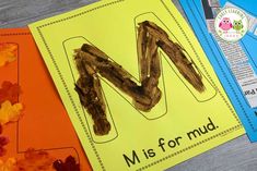 the letter m is for mud next to an orange and yellow paper with leaves on it