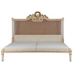 a white bed with gold trimming and headboard