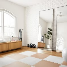 a large mirror sitting on top of a wooden floor next to a white brick wall