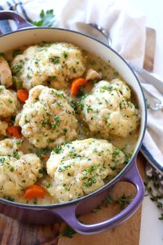 a pot filled with chicken and dumplings on top of a wooden cutting board