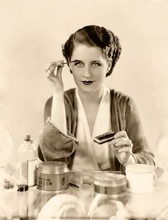 a black and white photo of a woman sitting at a table holding a cell phone