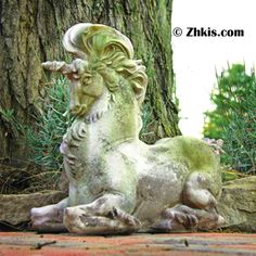 a statue of a ram sitting in front of a tree