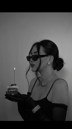 a woman wearing sunglasses holding a cake with a candle in it