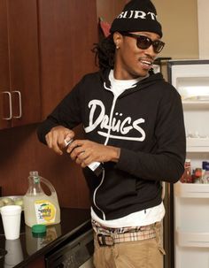 a man standing in front of an open refrigerator wearing sunglasses and a black hoodie