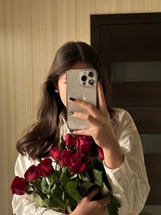 a woman taking a selfie while holding a bouquet of roses