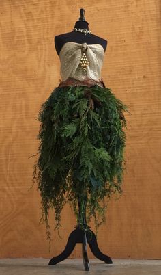 a mannequin is covered with green plants