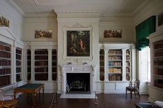 an empty room with many bookshelves and paintings on the walls, along with a fireplace