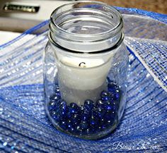 a glass jar filled with blue beads on top of a table