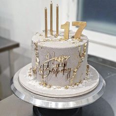 a white and gold birthday cake with candles on it's top that says happy birthday