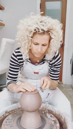 a woman is making a vase out of clay