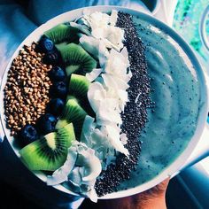 a bowl filled with fruit and nuts on top of a car dash board next to a person's hand