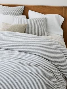 an unmade bed with white and grey striped linens