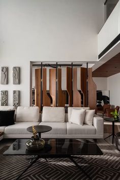 a modern living room with white couches and black coffee table in front of wooden partitions