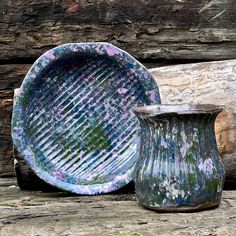 two vases sitting next to each other on top of a wooden table covered in green and purple paint