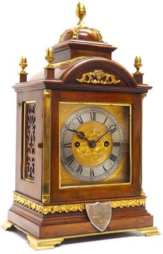 an antique wooden clock with gold trimmings and ornate decorations on the face, in front of a white background