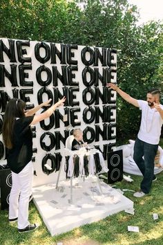 two people standing in front of a large piece of art that says, one one