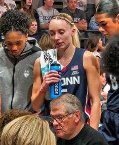 a group of people standing around each other in front of a basketball player holding a water bottle