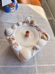 there is a candle holder made out of seashells on top of a bed