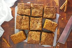 a cutting board topped with sliced up brownies next to a knife and napkins