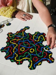 a person is making a colorful puzzle on the floor with scissors and paper towels in front of them