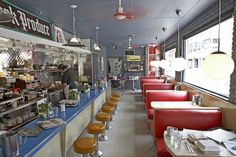 the inside of a restaurant with many tables and stools in front of it,