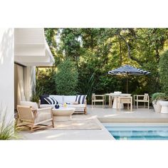 an outdoor living area with chairs, tables and umbrellas near a swimming pool surrounded by greenery