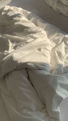 an unmade bed with white sheets and pillows