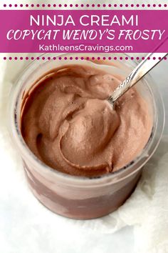 a small glass bowl filled with whipped cream and topped with chocolate frosting, on top of a white cloth