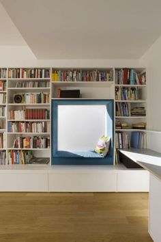 a bookshelf filled with lots of books next to a desk and chair in front of a mirror