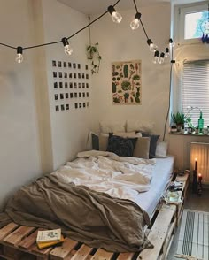 a bed made out of wooden pallets in a room with lights hanging from the ceiling