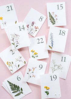 some cards with flowers and numbers are laid out on a pink surface, including one for each card