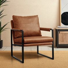 a brown leather chair sitting on top of a rug next to a potted plant