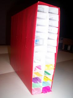 a large red book with many different colored papers on the front and back cover, sitting on top of a white table