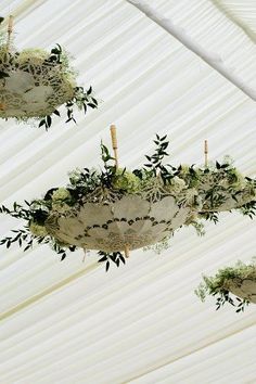 the ceiling is covered with white draping and hanging planters filled with greenery