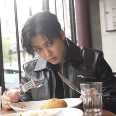 a man sitting at a table eating food with a fork and knife in his hand