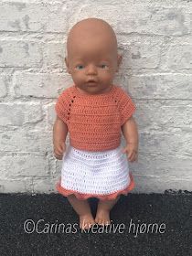 a baby doll is sitting on the ground next to a white brick wall wearing an orange shirt and white skirt