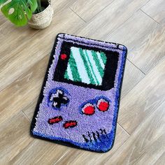 a rug with a gameboy design on the floor next to a potted plant