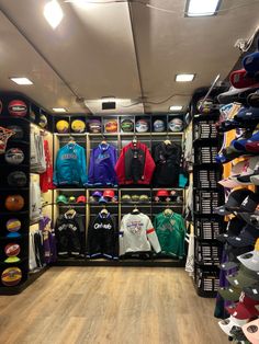 the inside of a clothing store with lots of shirts and hats on display in it