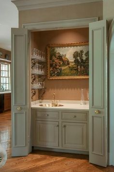 an open door leading to a kitchen with cabinets and wine glasses on the counter top