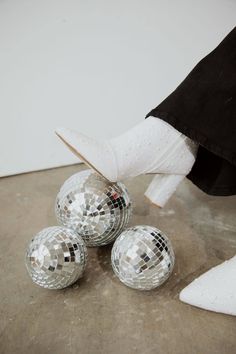 three disco balls are sitting on the floor next to a pair of white socks