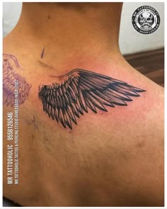 the back of a woman's neck with an angel wing tattoo on her chest