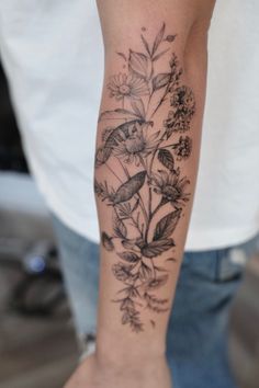 a woman's arm with flowers and birds tattooed on the back of her arm