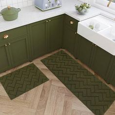 a kitchen with green cabinets and white counter tops, an area rug that looks like herringbones