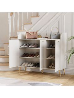 a white cabinet with shoes and purses on it in front of some staircase steps