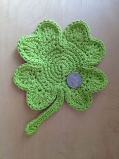 a green crocheted clover with a coin on it