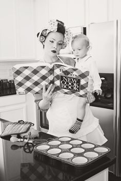 a woman reading a book to a baby in front of muffin tins on the counter