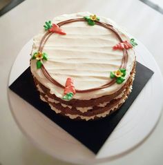 a cake sitting on top of a white plate covered in frosted icing and decorations